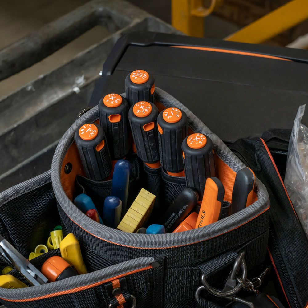 Top view of a tool kit with an assortment of tools including six orange and black screwdrivers.