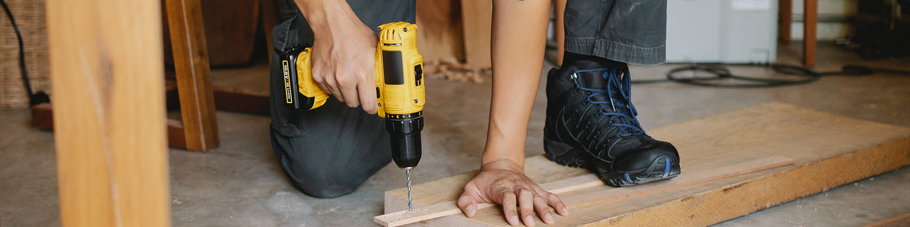Person drilling a yellow and black power drill into a piece of wood.