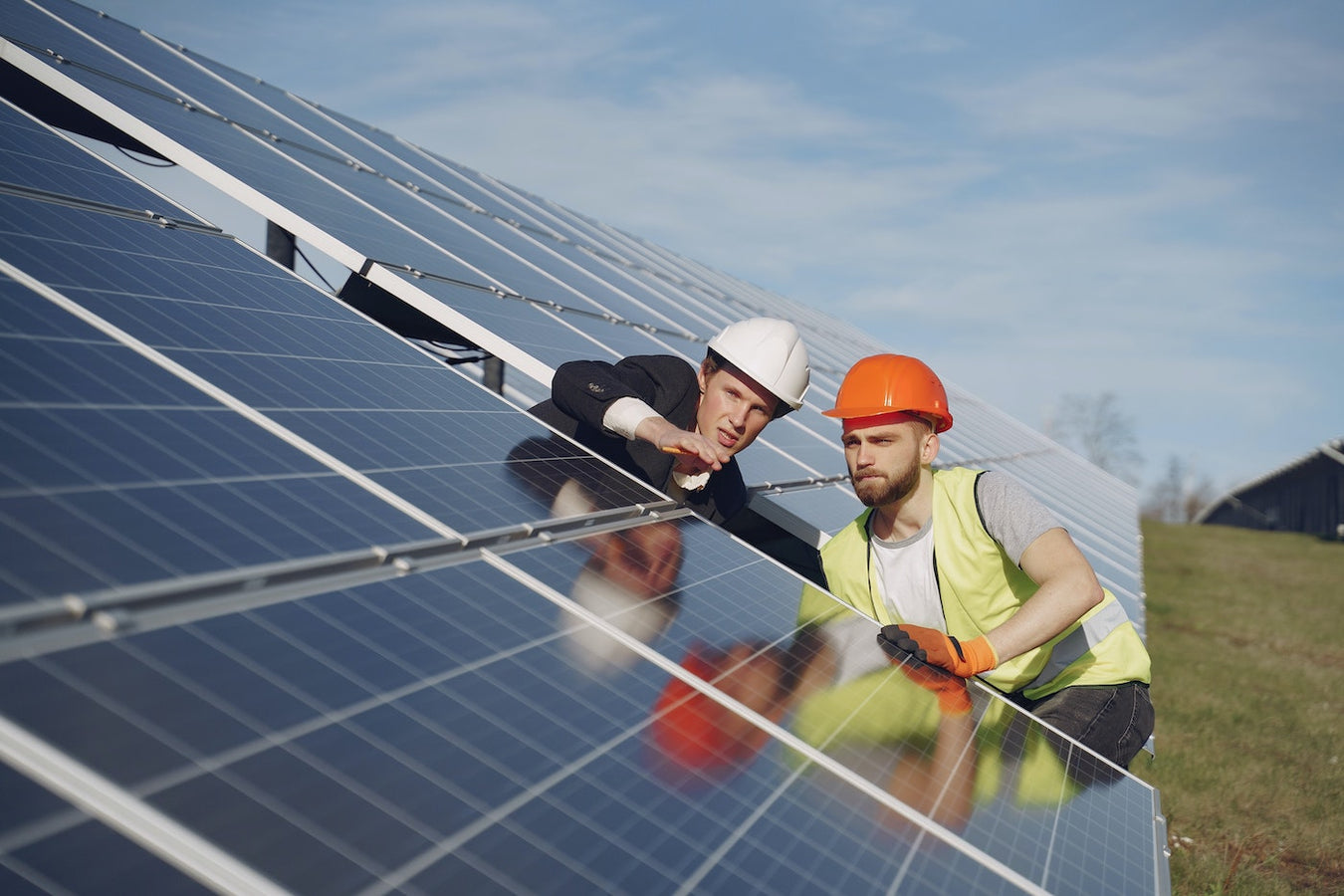 Two people in hardhats looking at solar panels.
