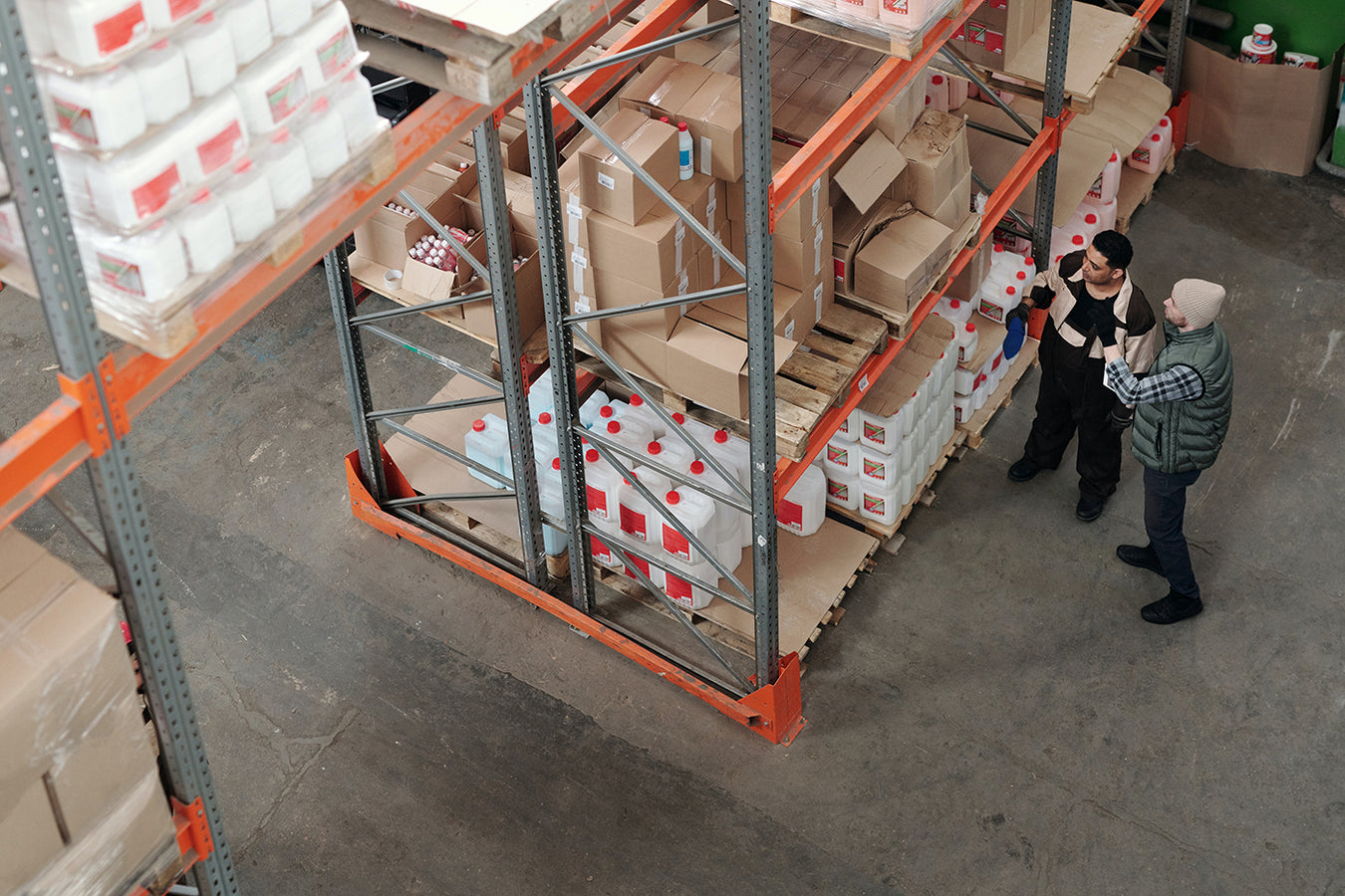 Top view of a warehouse full of boxes with two people looking at the boxes.