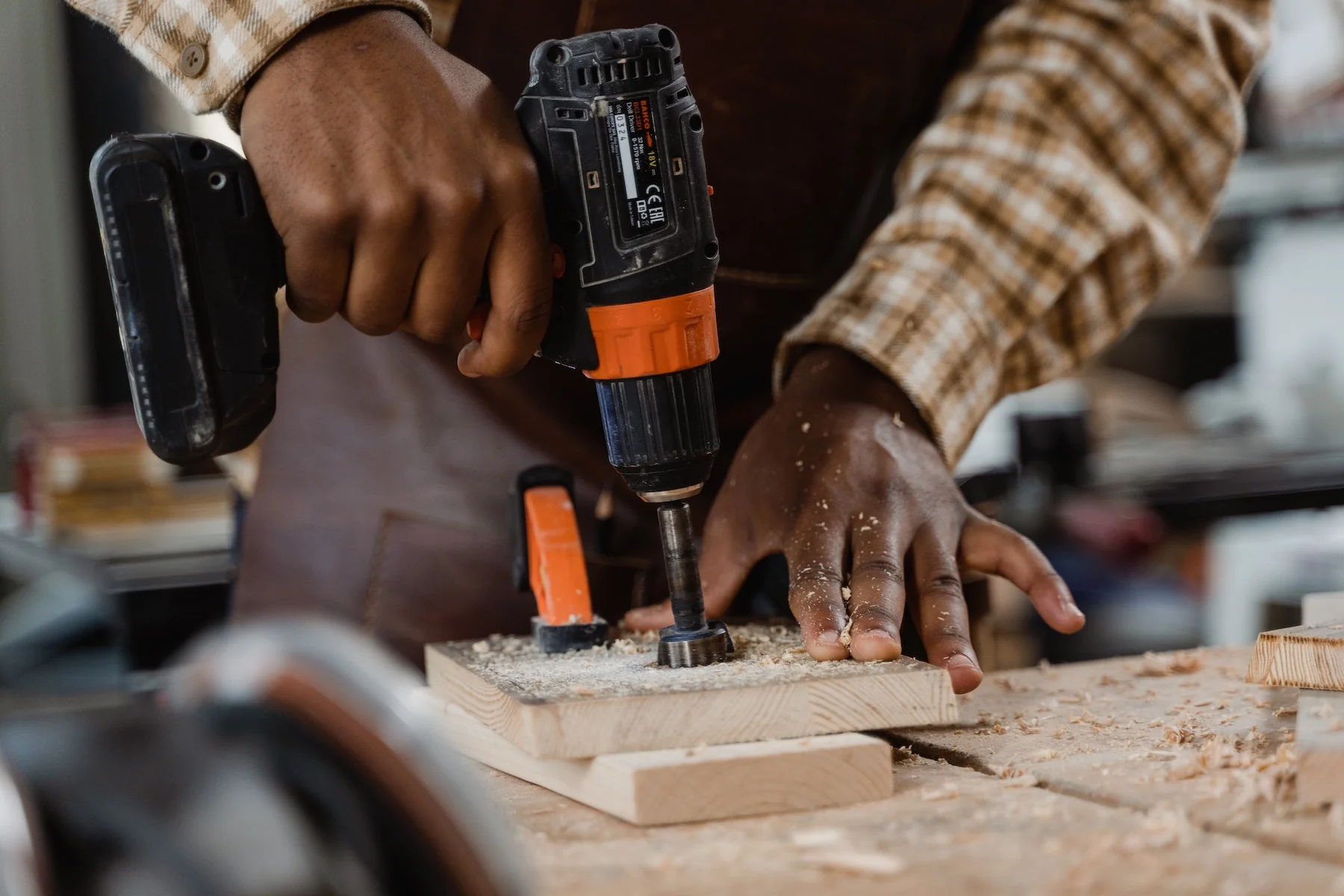 Man holding power drilling and drilling wooden block.