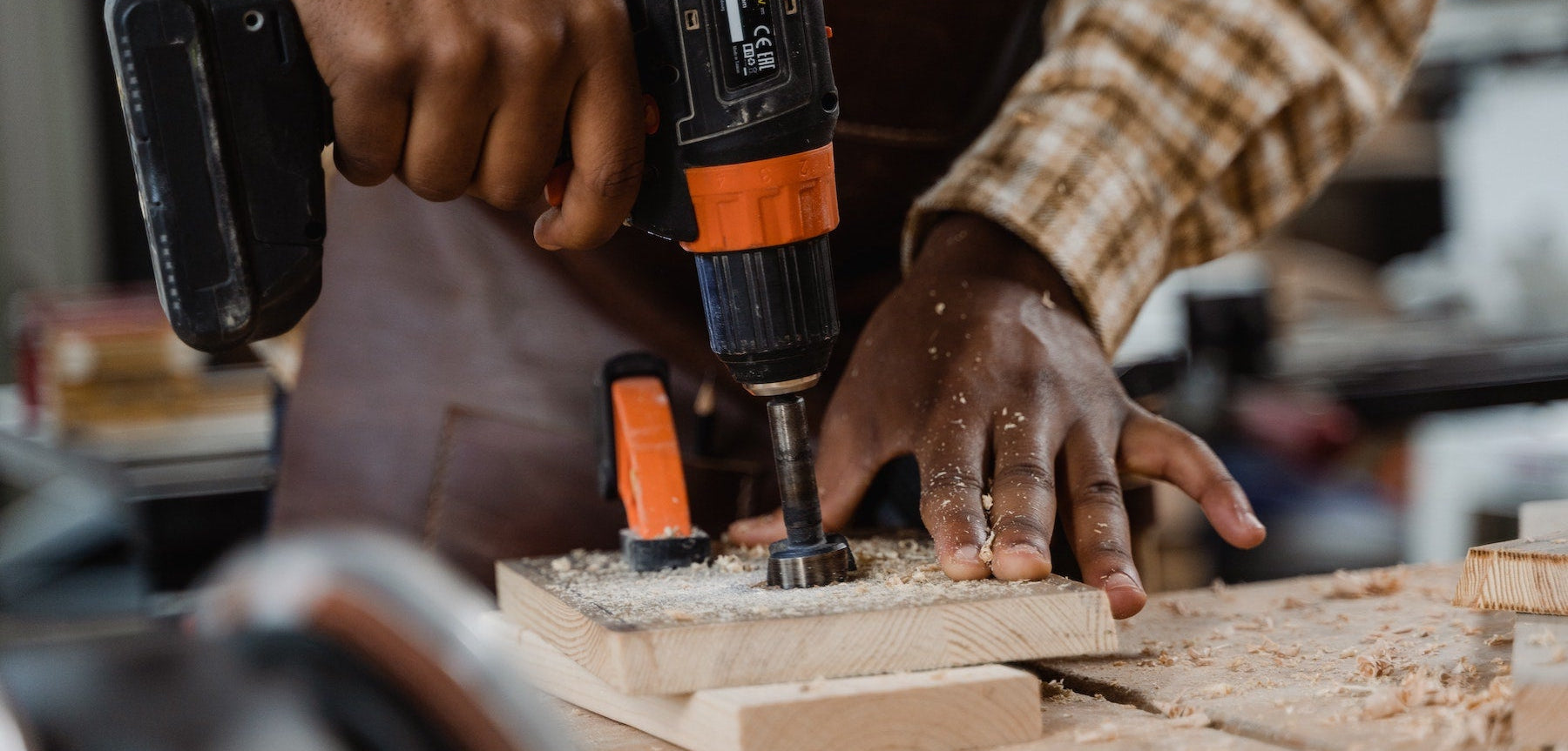 Man holding power drilling and drilling wooden block.