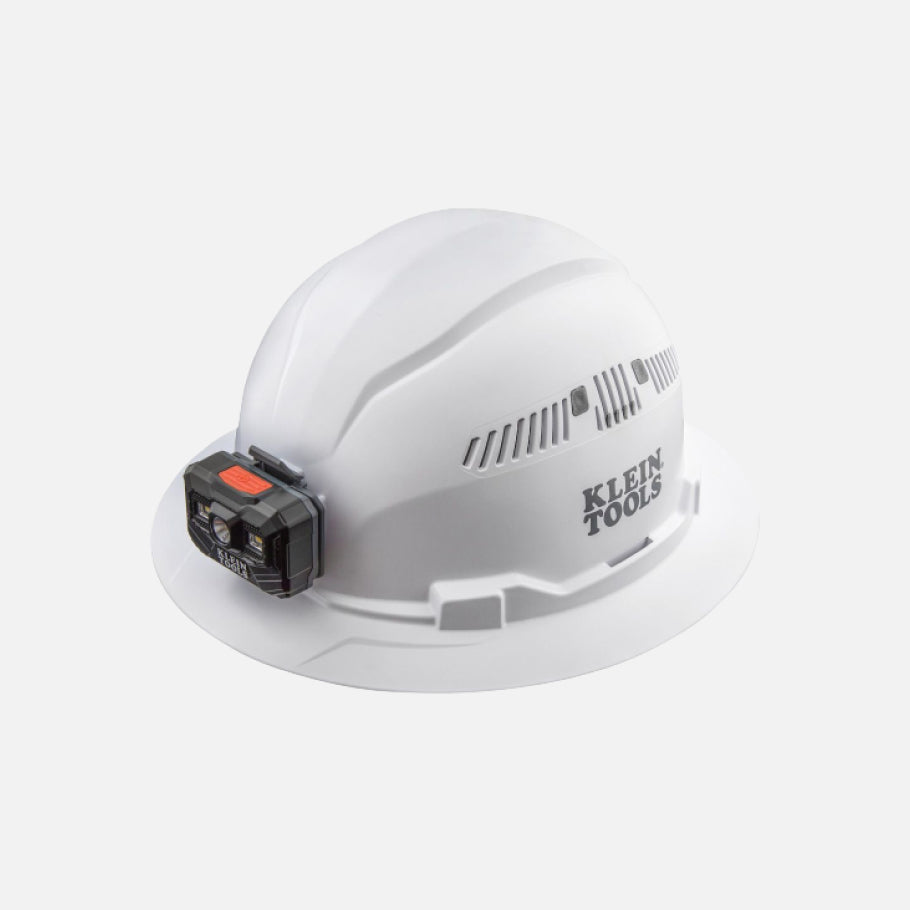 A white hardhat with a headlamp on the front of the hardhat on a light grey background.